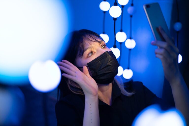 Una foto di una donna che indossa una maschera ed esegue l'autenticazione facciale utilizzando il suo telefono