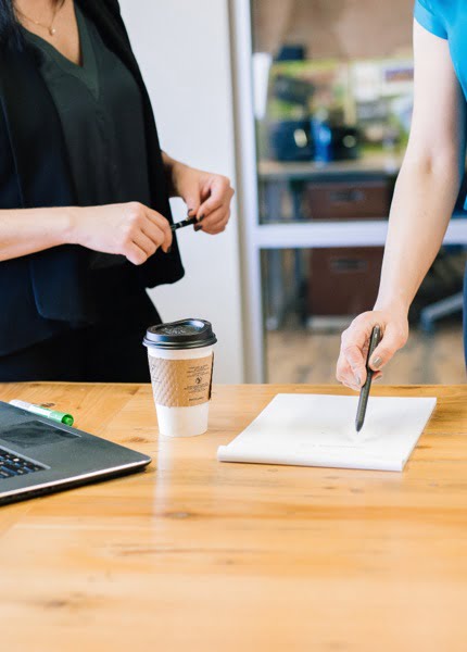 Close up shot of two colleagues discussing a document on a table. AML KYC compliance software