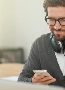 Telcos / MNOs verification: Photo of a young man using a smartphone. Enhanced DBS checks offered by a UK DIATF certified IDSP for employee hire.